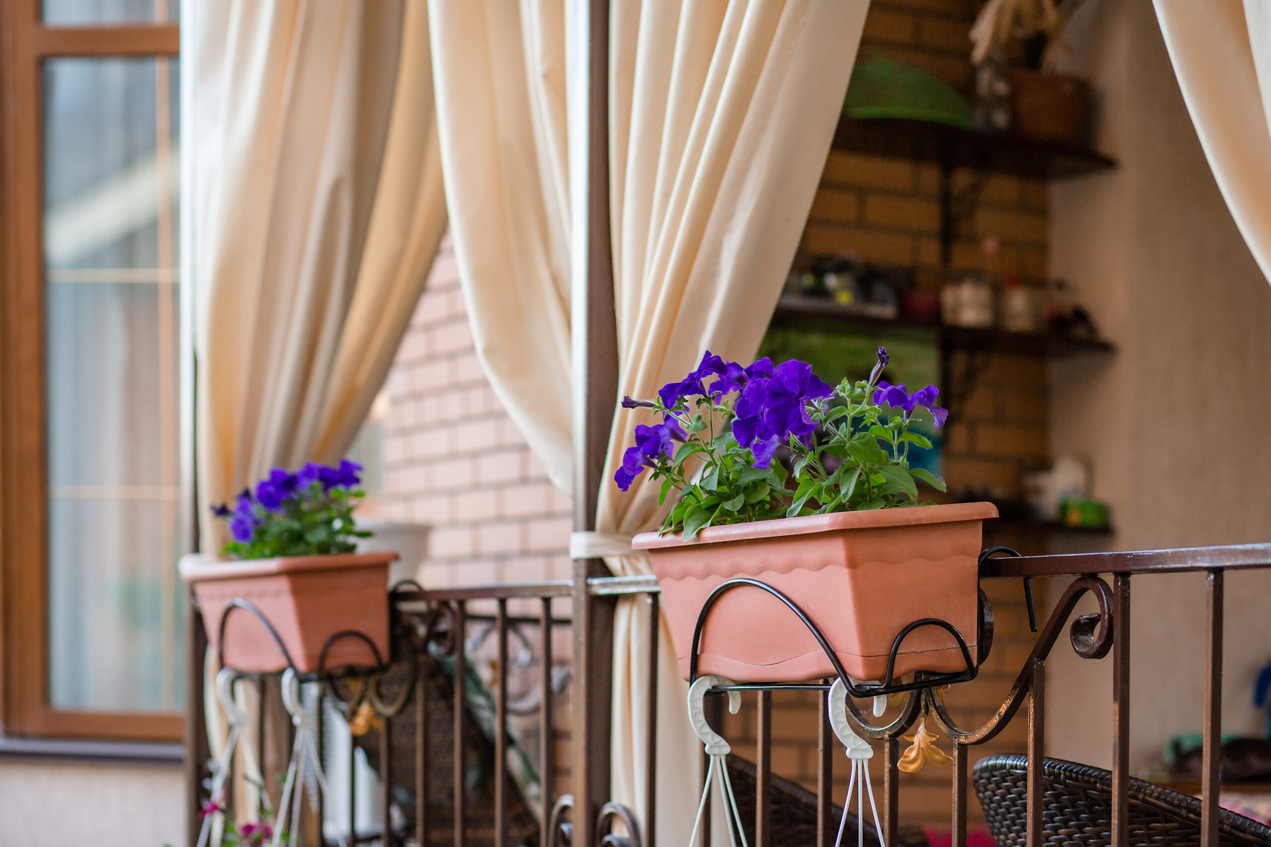 Flowers in hanging pots on the porch of the house. Comfort and beauty near the house.